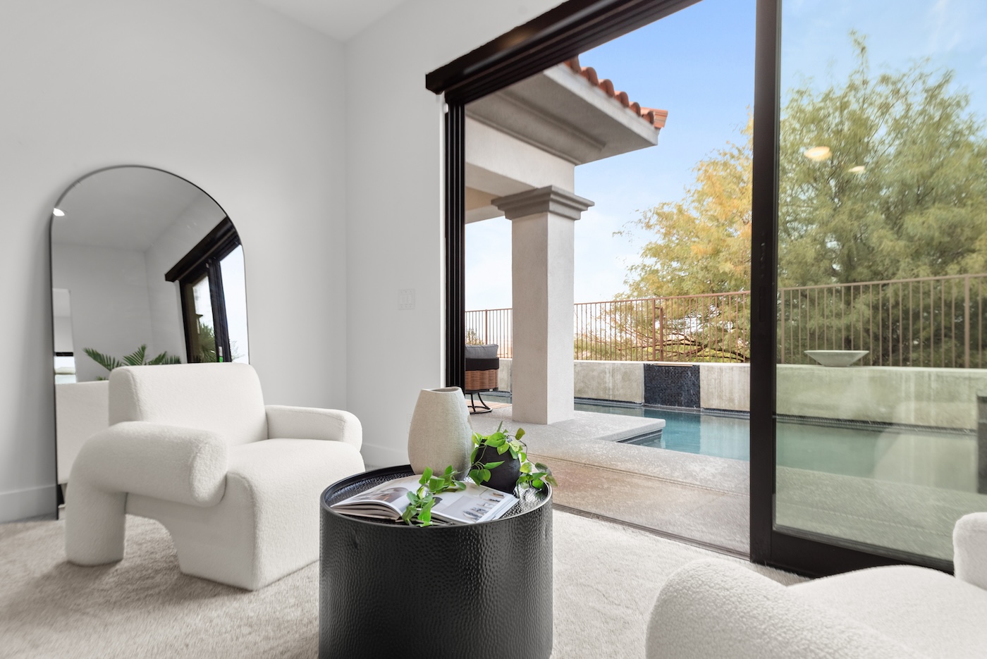 Staged living room with natural wood furniture, abstract art, and warm natural light streaming through windows at Camino La Venta Las Vegas