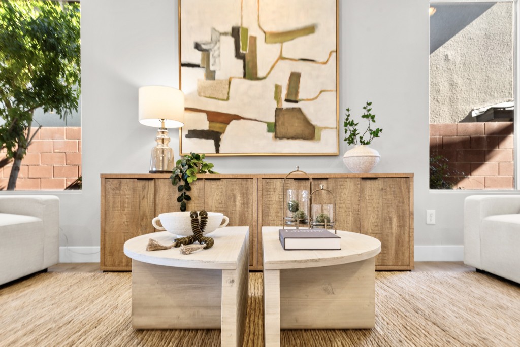 Staged luxury family room with white bouclé accent chairs, hammered metal side table, and floor-to-ceiling window overlooking pool at Kesington Dr Las Vegas