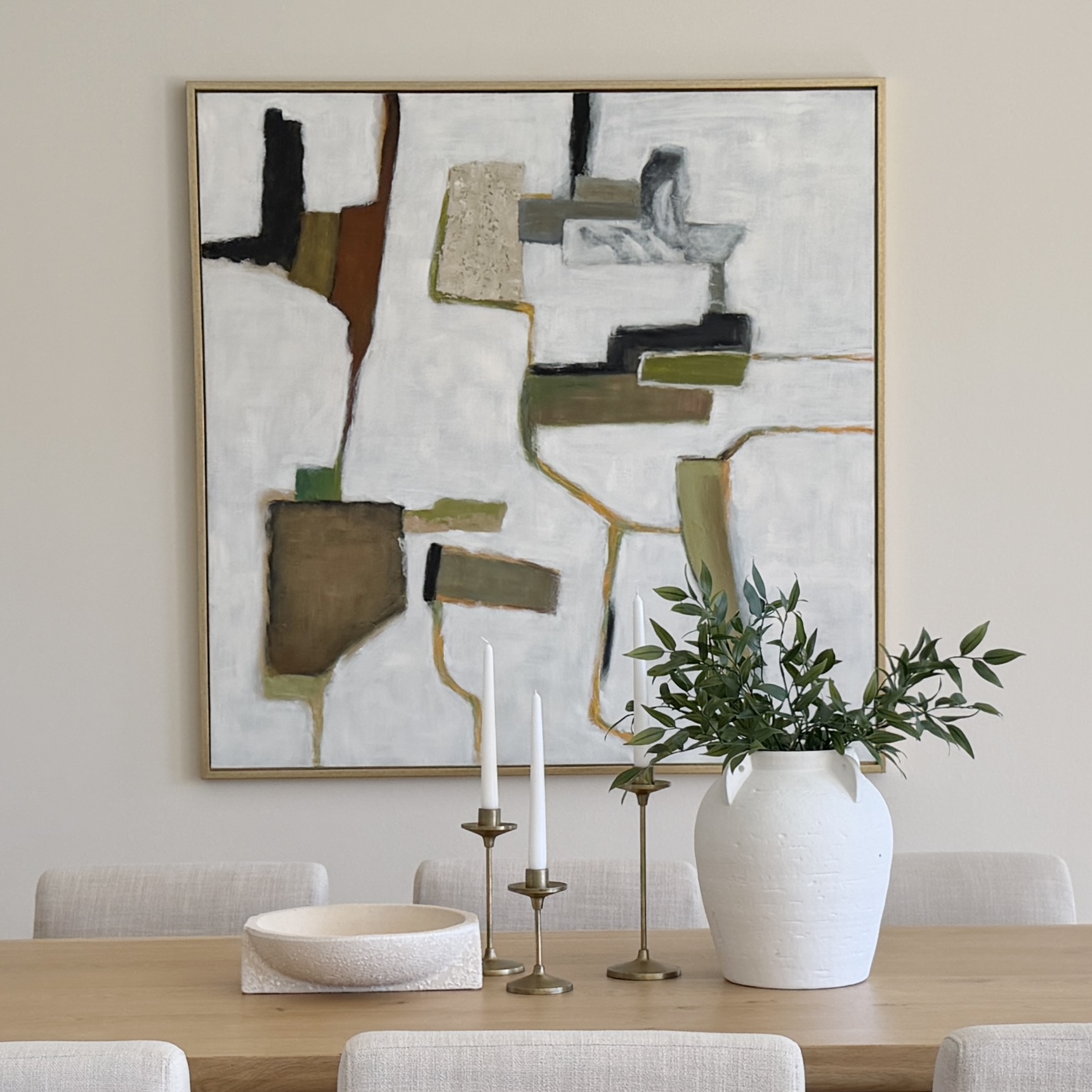 Staged dining table vignette with abstract art and candleholders — the kind of detail buyers notice when staging is handled well